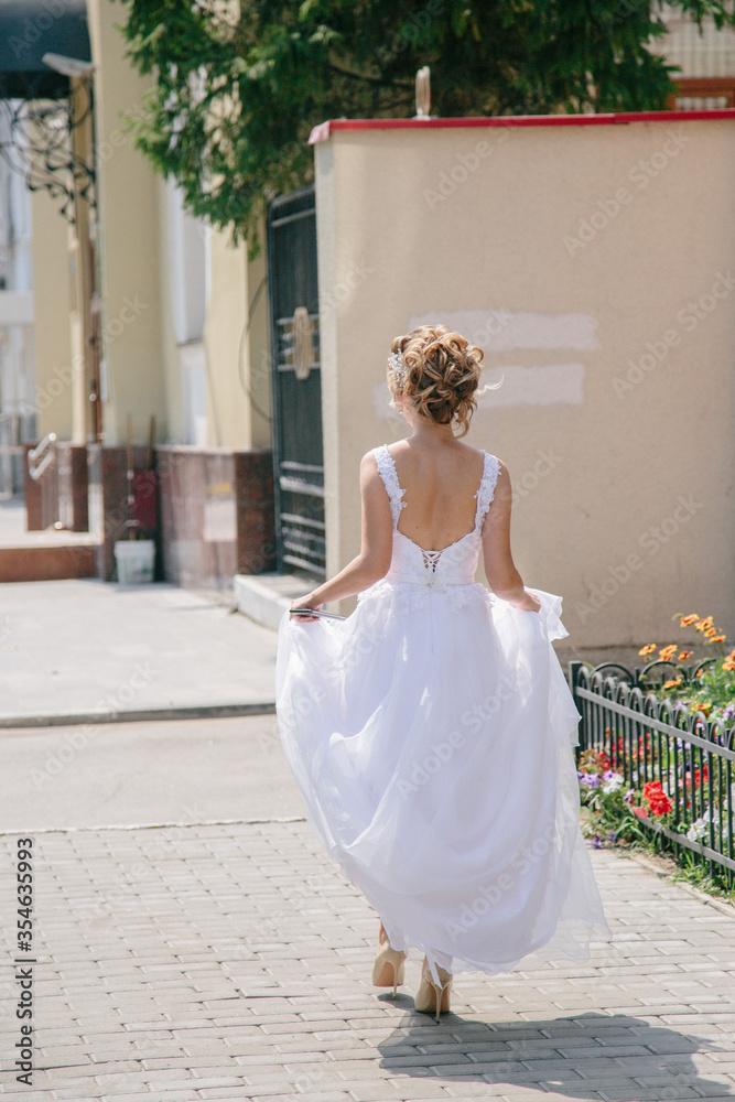 Fototapeta premium bride in a white dress walks down the street