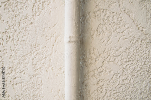 white water pipe in a white wall of small textures  photo