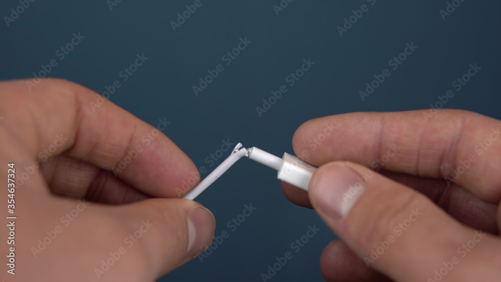 Torn USB cable close-up. A man holds a torn wire in his hands. Wire wear Torn USB cable close-up. A man holds a torn wire in his hands. Wire wear