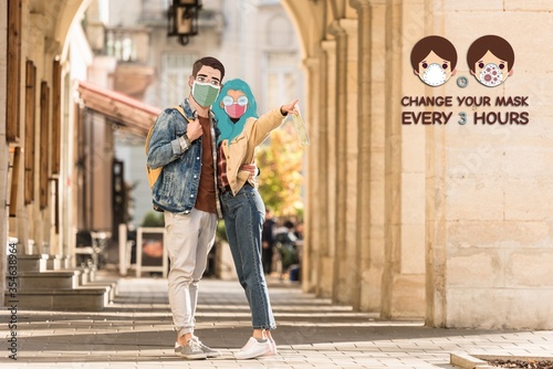 couple of tourists with illustrated faces in medical masks hugging on street and pointing with finger away, change your mask every 3 hours illustration