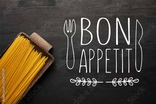 top view of raw spaghetti on black wooden background, bon appetit illustration