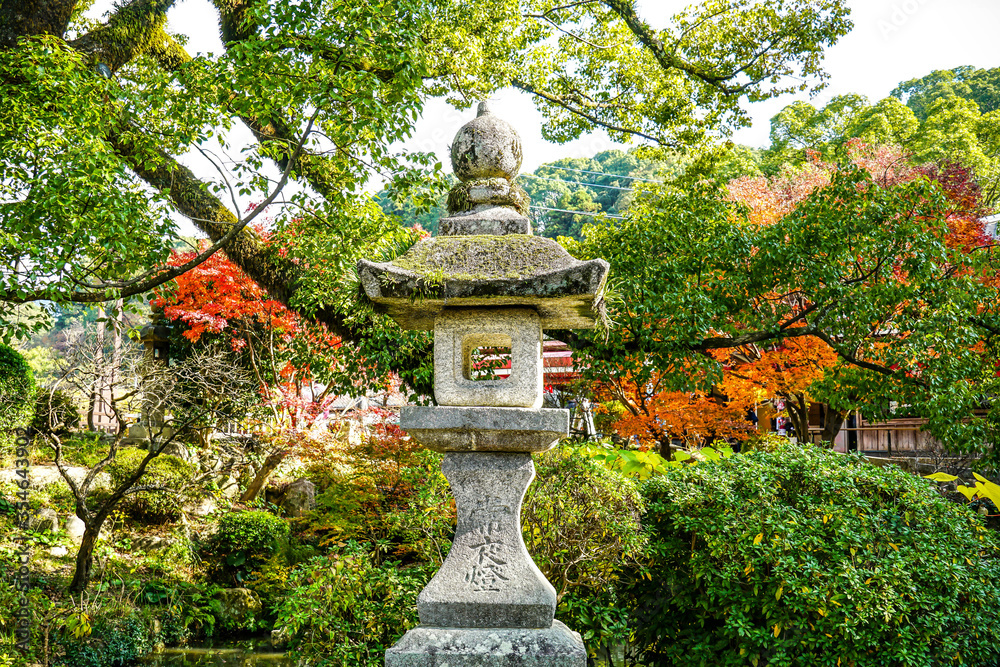 A peaceful background of autumn Japanese garden and a traditional granite stone lamp post in the middle