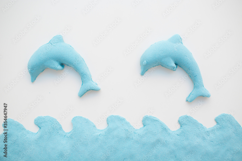 Kinetic sand - modern toy for children development. Form dolphin and blue water. Kinetic sand - modern toy for children development. Form dolphin and blue water.