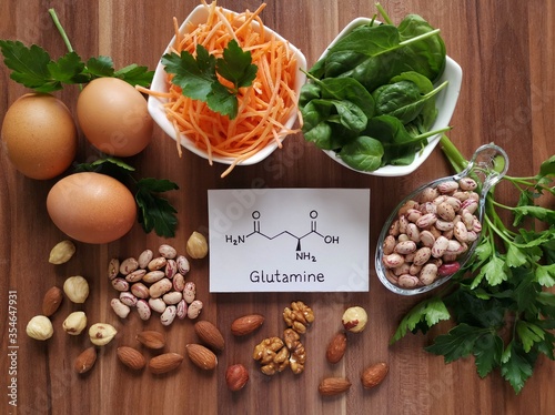 Food rich in glutamine with structural chemical formula of glutamine molecule. Food for training and exercise: spinach, eggs, parsley, carrot, beans, almond, walnut. Bodybuilding, sport nutrition. photo