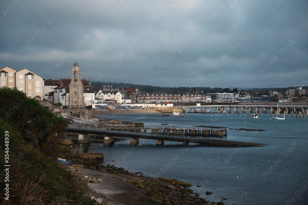 Morning city view in the south of England on the shore of a sea bay with a pier and boats. Swanage Bay, United Kingdom