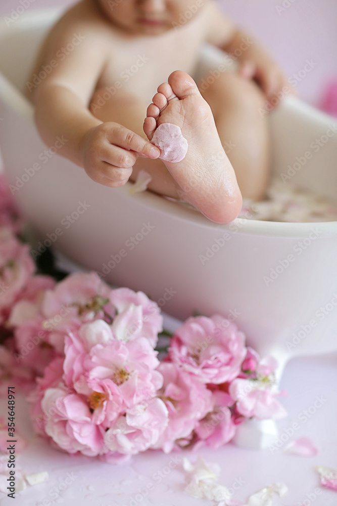 Leg of a little girl in close-up. The concept of foot care. Pedicure. Soft focus. Small fingers against a background of pink roses.