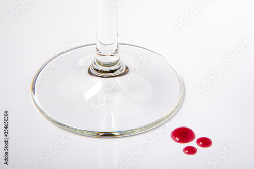 Base de copa de cristal de vino con tres gotas de vino sobre fondo blanco 