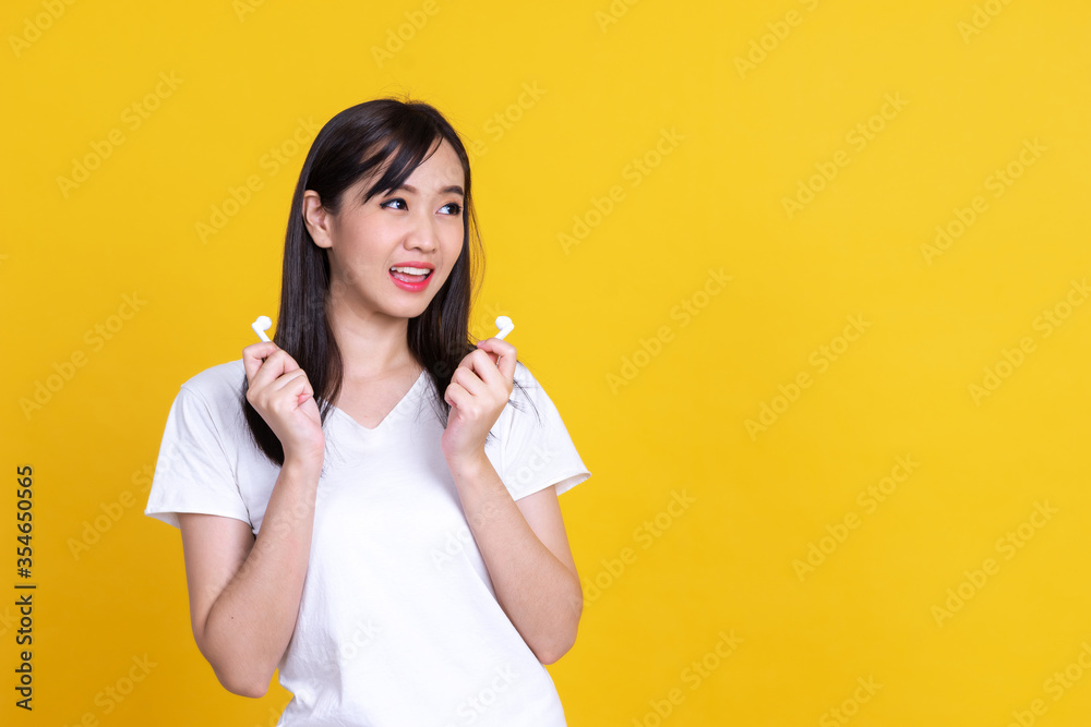 Happy Asian woman 20s take off the wireless earphones smiling and dancing isolated over background Happy Asian woman 20s take off the wireless earphones smiling and dancing isolated over background