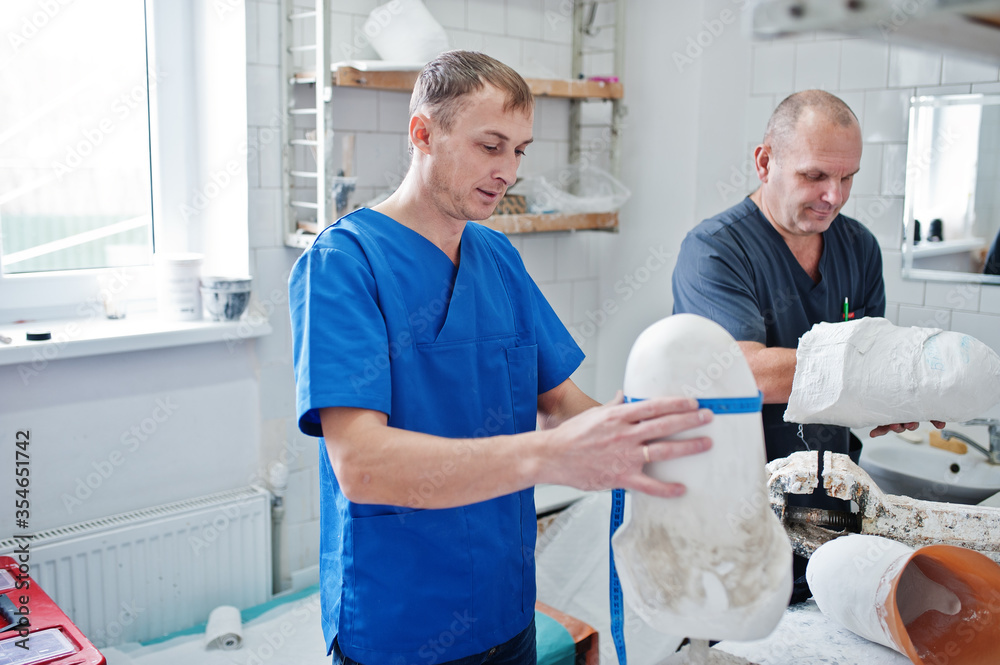 Fototapeta premium Two prosthetist man workers making prosthetic leg while working in laboratory.