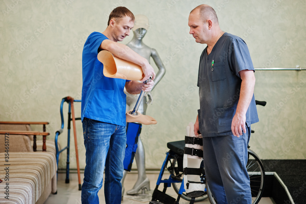 Two prosthetist man workers with prosthetic leg working in laboratory.
