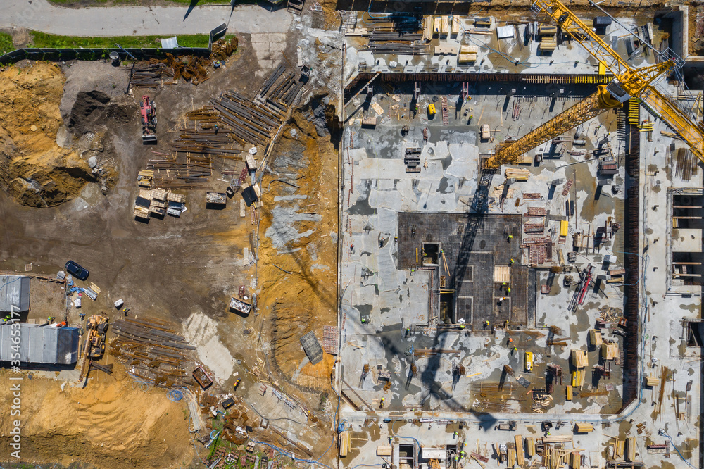 Fototapeta premium Contstruction Site from above. Aerial view of new apartment under construction. People working. Top view industrial place.