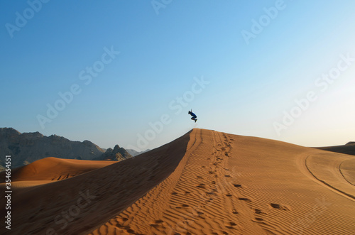 Boy takes giant leap off a sand dune in the Al Faya Desert near Dubai