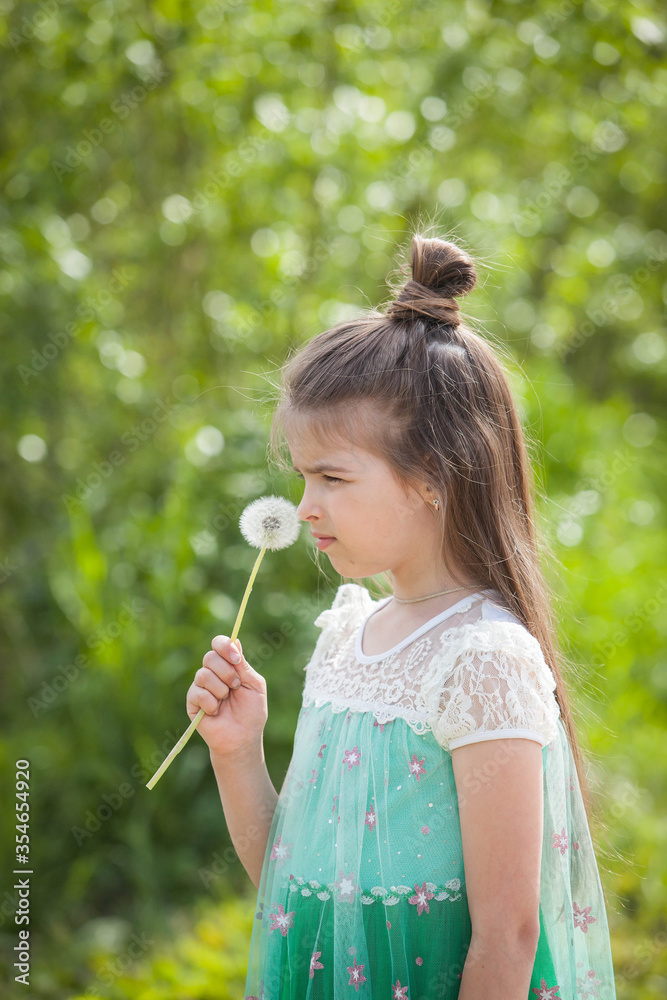 a beautiful girl in a green dress plays with a dandelion on a Sunny summer day a beautiful girl in a green dress plays with a dandelion on a Sunny summer day