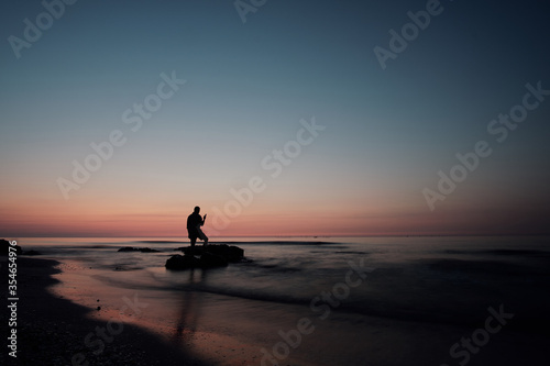 silhouette of a man standing on the beach at sunrise