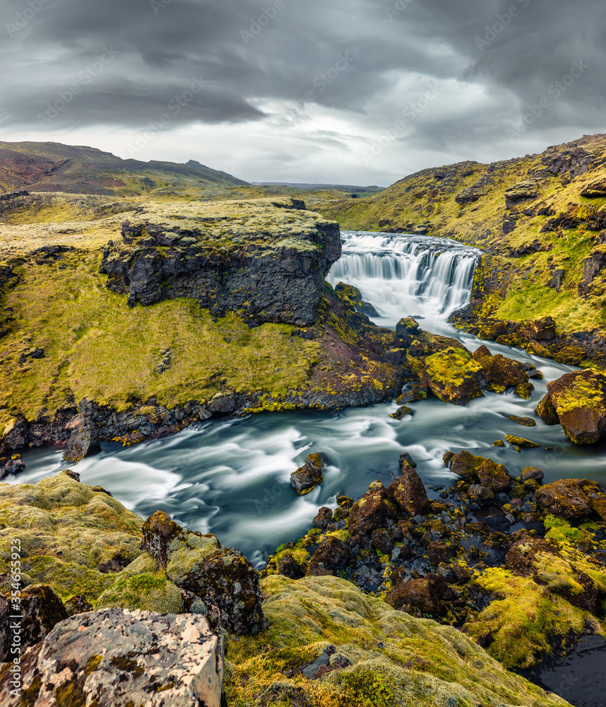 Dramatic summer scene of waterfall on Skoga river. Gloomy morning view from the tourist trek from famous Skogafoss waterfall to the top of the river, Iceland, Europe. Dramatic summer scene of waterfall on Skoga river. Gloomy morning view from the tourist trek from famous Skogafoss waterfall to the top of the river, Iceland, Europe.