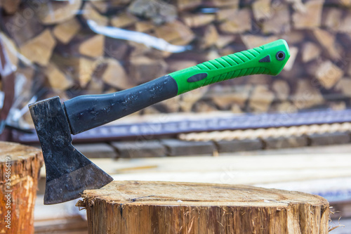 A metal axe stands stuck in a wooden stump after chopping wood