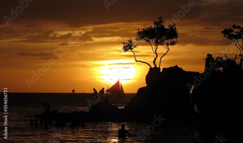 Yellow orange sunset on the sea. Small waves  beautiful sky  yellow sun and silhouettes of people. Thailand  Phuket  in the evening.
