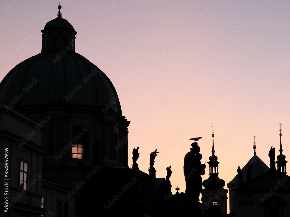 Silhouettes of ancient European buildings on a pink sky background.
