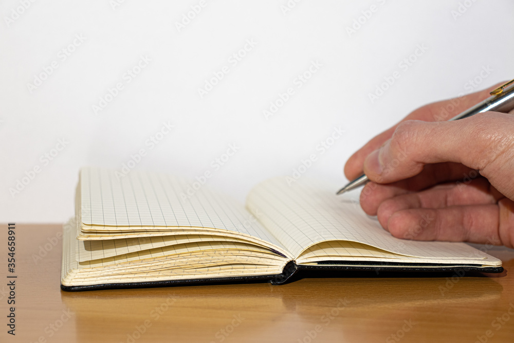 Open notebook and hand on a wooden table Open notebook and hand on a wooden table