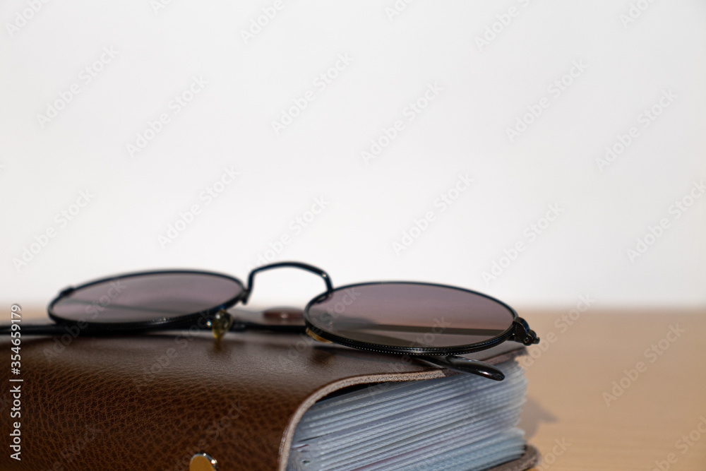 Glasses and brown notebook on a wooden table Glasses and brown notebook on a wooden table