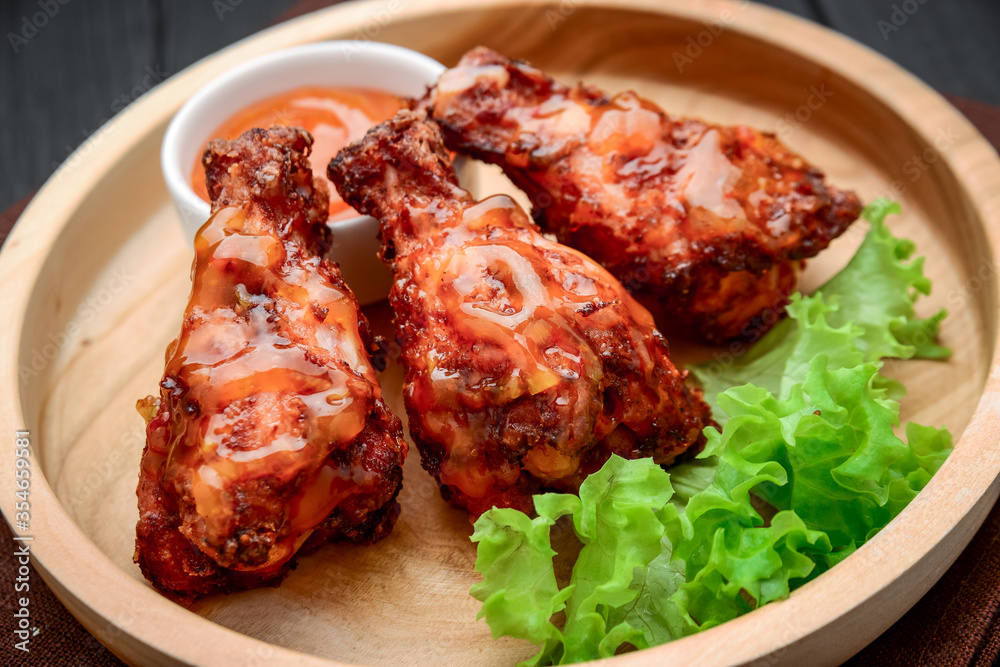 BBQ chicken wings with spicy sauce on a wooden plate BBQ chicken wings with spicy sauce on a wooden plate