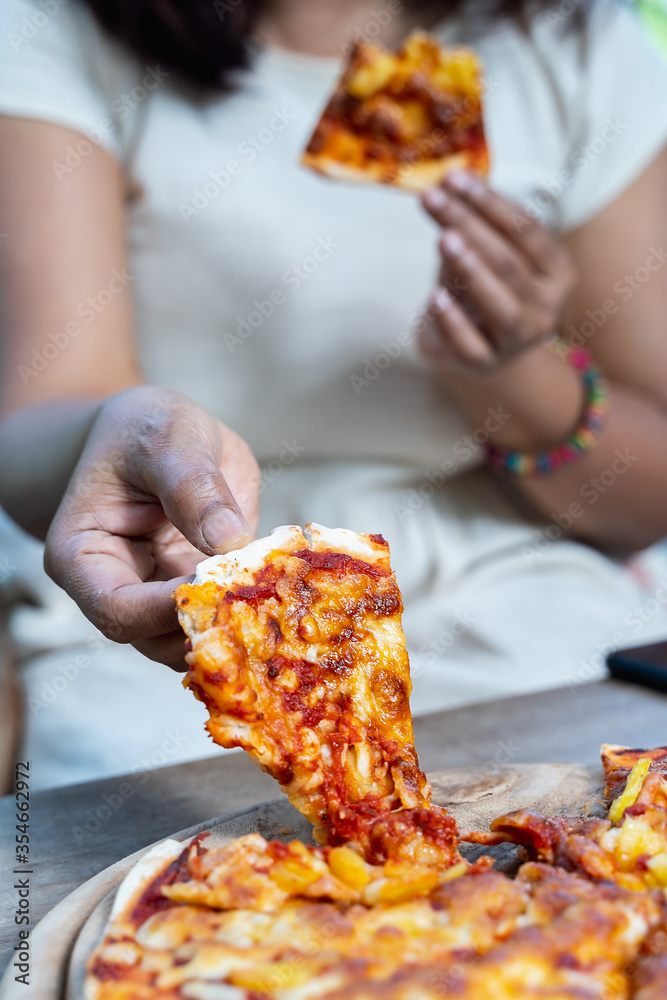 Female’s hand holding slice a pizza out of the wooden tray..