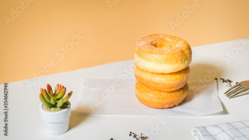 Homemade deep fried donuts in stack with sugar standing on crumpled paper with white table. photo