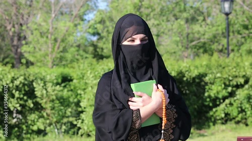 An Islamic woman in national women's clothing holds a holy book with prayers in her hands. photo