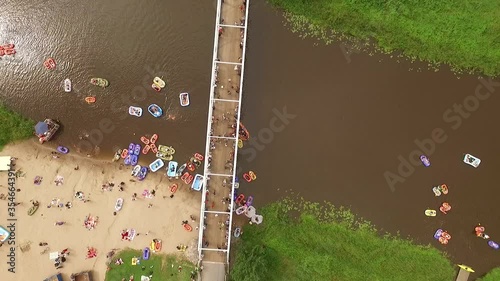 A bird's-eye- view shows people of all ages participating in Kaljakellunta, the beer floating festival in Finland, riding on inflatable boats and inner tubes down a river. photo