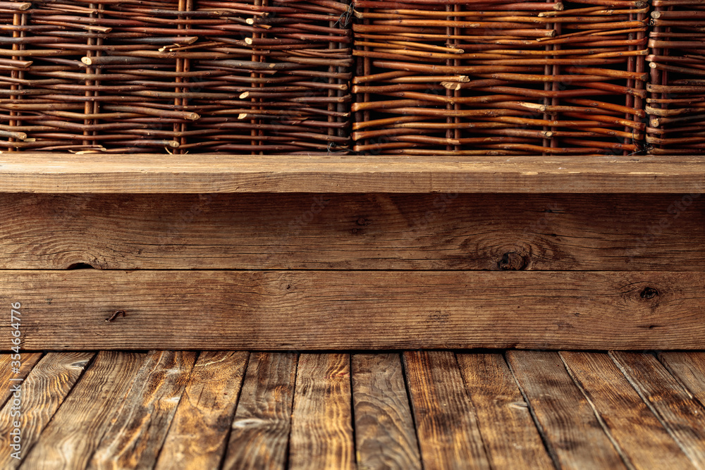 Old wooden table and a wicker fence. - obrazy, fototapety, plakaty 