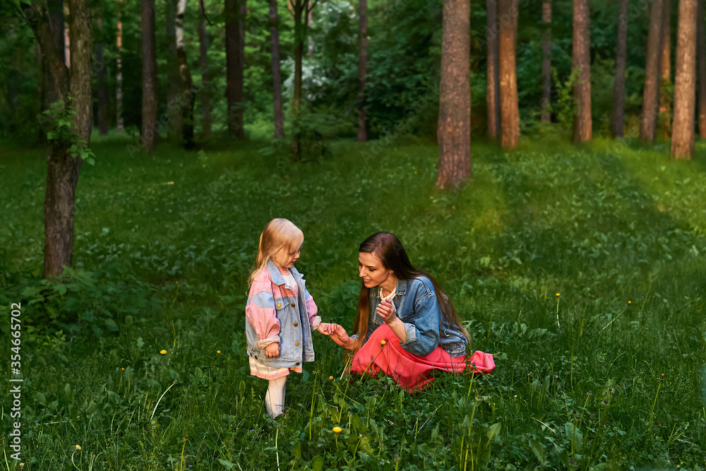 Fototapeta premium mom tells her daughter about the world while walking in the park