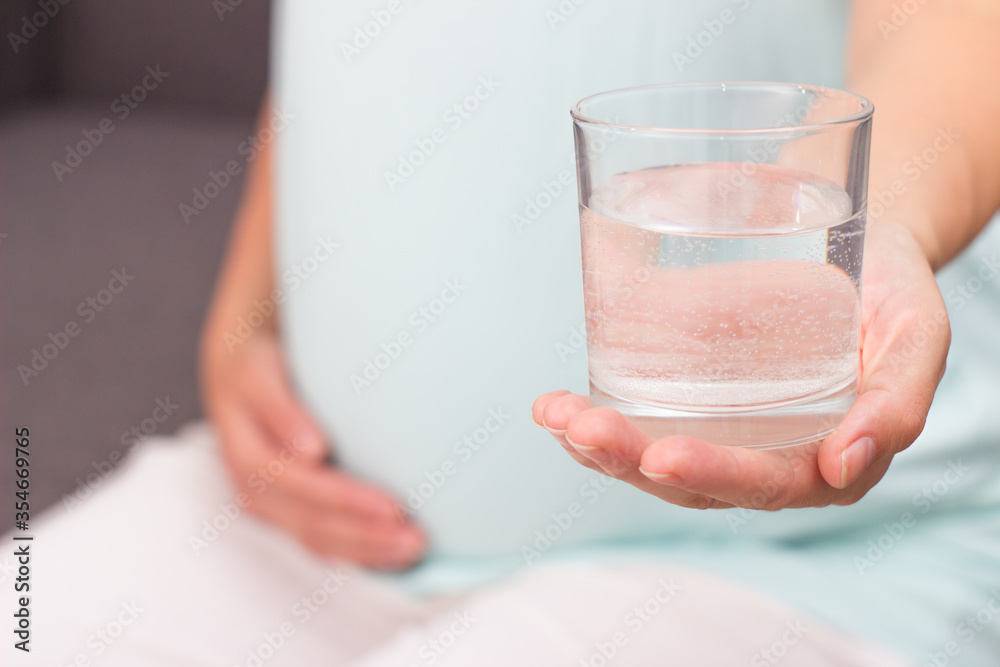 Pregnant drinks mineral water. The pregnant woman holds a glass of mineral water. Pregnant drinks mineral water. The pregnant woman holds a glass of mineral water.
