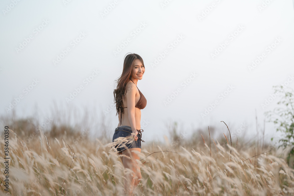 Beautiful blonde women in a brown bikini on a brown meadow with white flowers in the summer evenings. Beautiful blonde women in a brown bikini on a brown meadow with white flowers in the summer evenings.