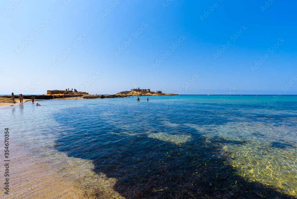 Beautiful crystal clear water. Isola delle Correnti (Currents Island), Portopalo di Capo Passero, Syracuse, Sicily. People bathing enjoying the beach.