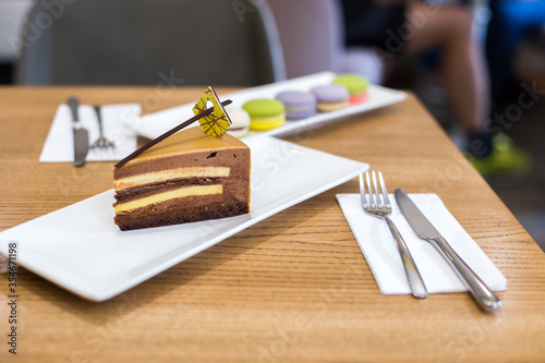  Chocolate yortt with a layer of mango on a white plate stands on a wooden table, closeup shot.