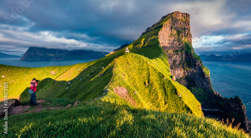 Photographer takes picture of Kallur Lighthouse, Kalsoy island. Incredible summer scene ofFaroe Islands, Denmark, Europe. Majestic seascape of Atlantic ocean. photo