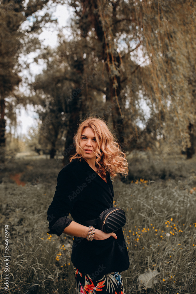 Photo session of a stylish girl outdoors. Young model on a background of wildflowers. Photo session of a stylish girl outdoors. Young model on a background of wildflowers.