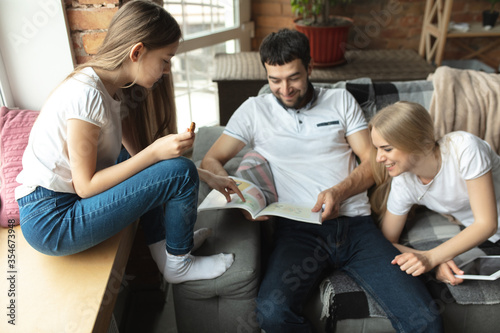 Mother, father and daughter at home having fun, comfort and cozy concept. Looks happy, cheerful and joyful. Beautiful caucasian family. Spending time together, reading books, talking, smiling.