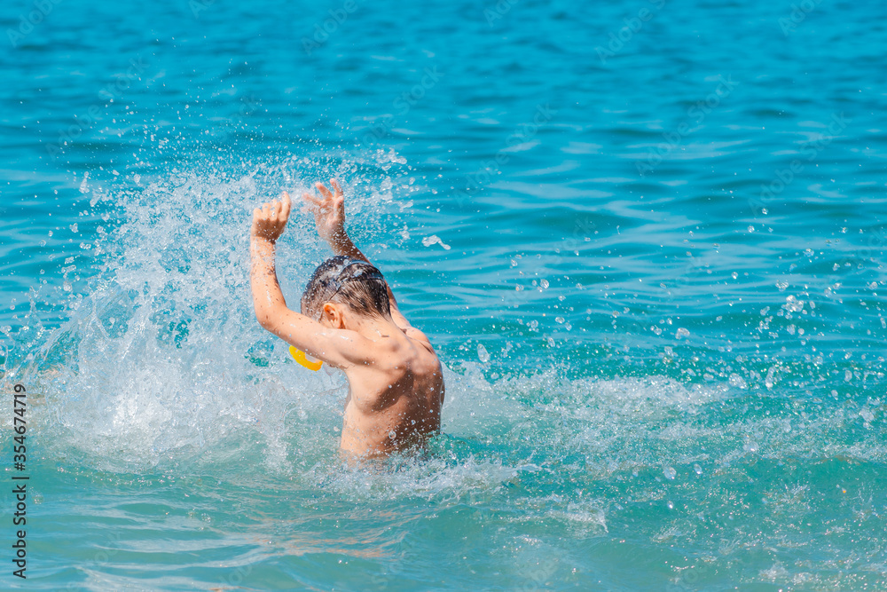 little girl in a swimsuit splashing her legs in the sea