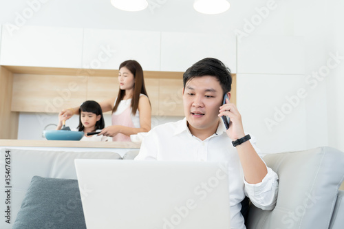 asian family activity concept, dad busy working from home, mom and kids learning cooking at kitchen room