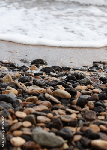 Different texture on the beach - water and sand, stones and pebbles, waves and splashes.