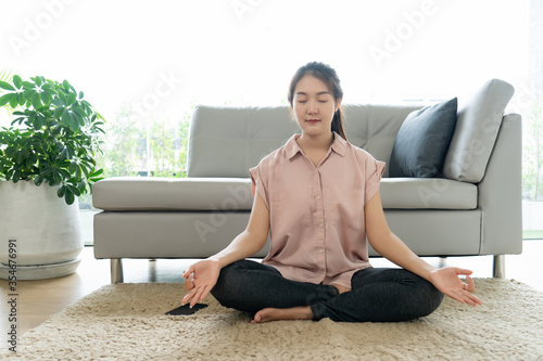 Asian young woman resting exercise by pose yoga meditation sit on carpet floor at home