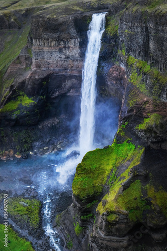 Dramatic view on a beautiful high waterfall in Iceland. It is located on the South of the island. Green and black coloured landscape.