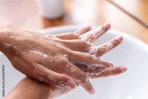 Detail of Woman's hands using soap and washing hands under the water tap