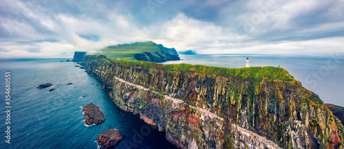 Panoramic view from flying drone of Mykines island with old lighthouse. Gloomy summer scene of Faroe Islands, Denmark, Europe. Stunning seascape of Atlantic ocean. photo