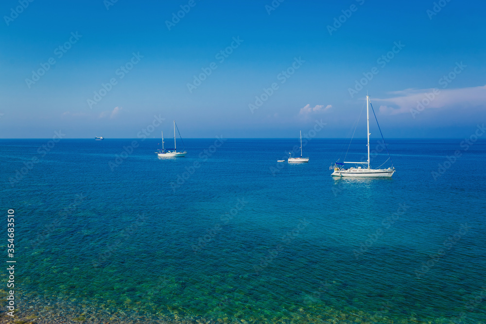 yachts sailing in a Mediterranean sea on a clear sunny day, Greece. Blue sky with white clouds. Idyllic seascape. Sport and recreation theme