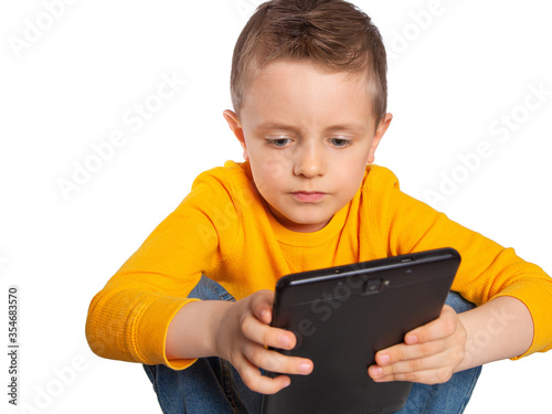 The child is engaged on a tablet. Training in using the Internet, tablet computers, smartphones, digital technologies. Working on a personal computer, teaching children programming and web design. photo