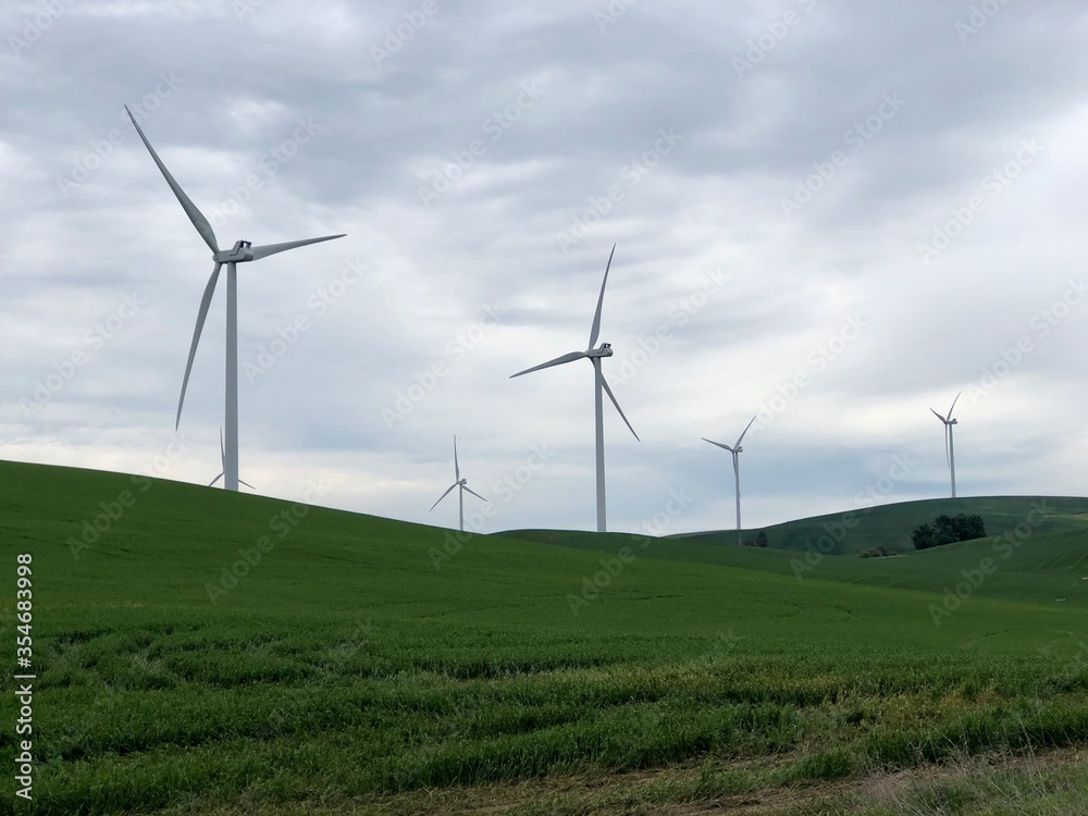 Group of wind turbines spinning on an overcast and cloudy day Group of wind turbines spinning on an overcast and cloudy day