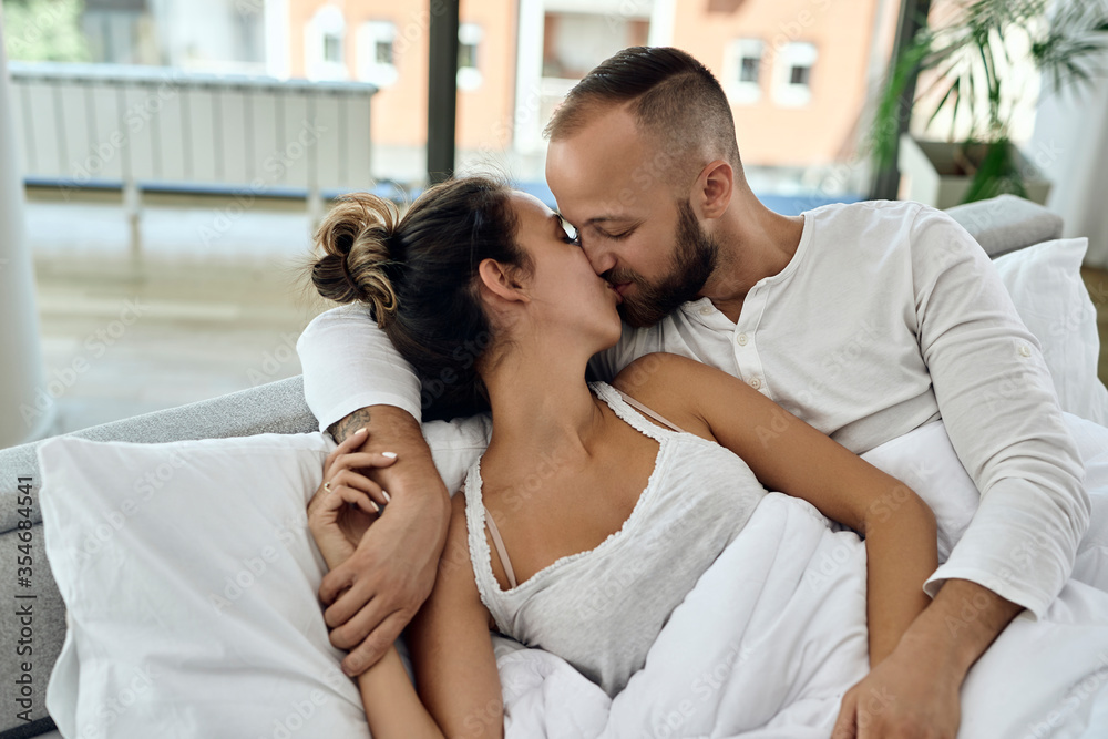 Loving couple kissing while waking up together in the morning. Loving couple kissing while waking up together in the morning.