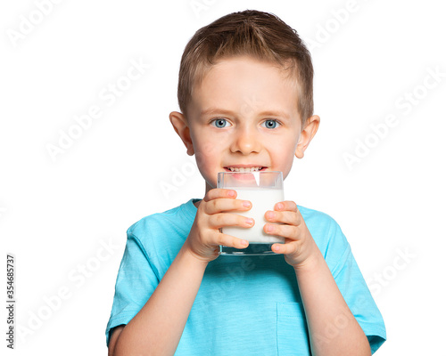 The child drinks milk. A beautiful European five-year-old boy with blue eyes drinks milk from a glass. Benefits of dairy products. Healthy diet. Portrait on a white background.